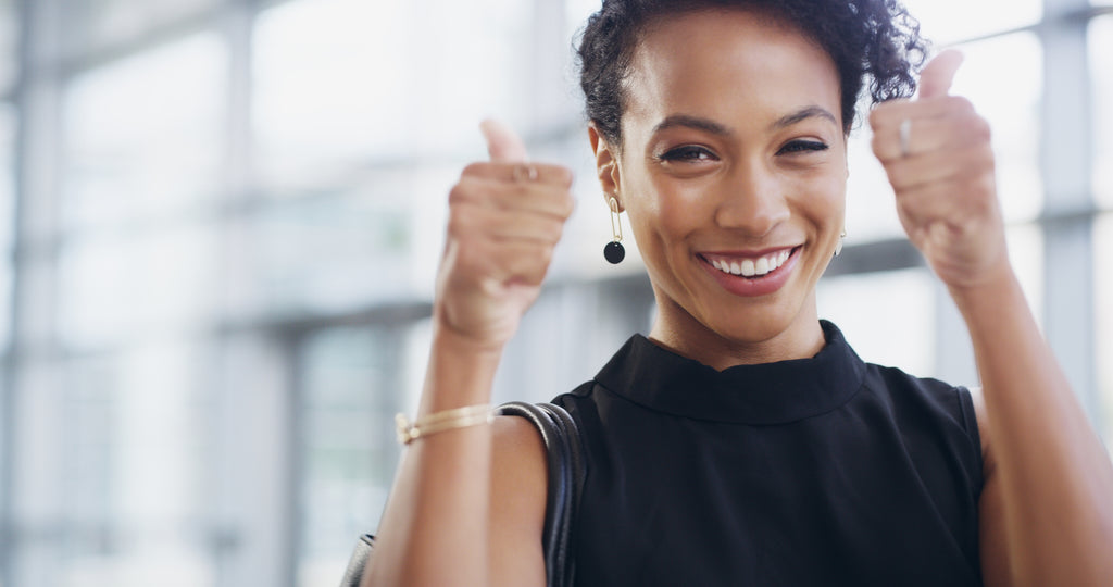 Woman with a black tank top, smiling and giving two thumbs up.